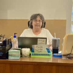 Paula sits at the Agape registration desk, ready to welcome clients with a smile.